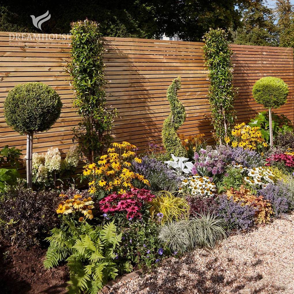 35-y-tuong-thiet-ke-canh-quan-san-vuon-cho-nam-2025-cho-nguoi-dam-me-11 Một khu vườn rộng lớn với nhiều loại cây xanh, cây bụi và cây nhỏ đầy màu sắc.