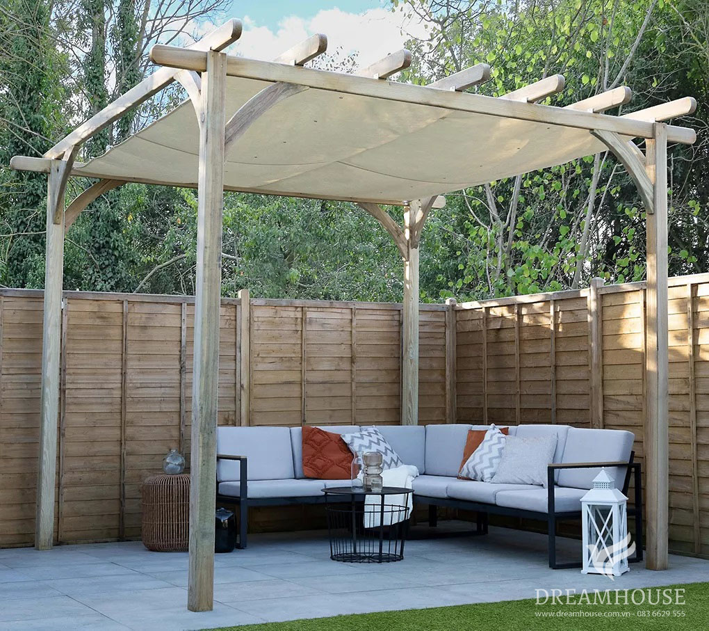 35-y-tuong-thiet-ke-canh-quan-san-vuon-cho-nam-2025-cho-nguoi-dam-me-12 Giàn che bằng gỗ ở góc vườn, tạo bóng mát cho chiếc ghế sofa ngoài trời màu đen và xám sành điệu trong khu vực tiếp khách ấm cúng.